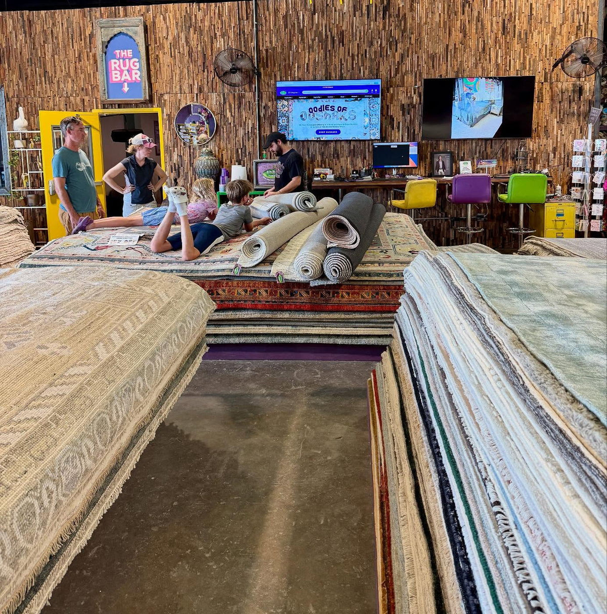 Customers relaxing on the rug stacks beside The Rug Bar inside the showroom